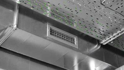 Sistema de ventilação industrial instalado em cozinha de restaurante, com duto de exaustão e grelhas para circulação de ar eficiente.